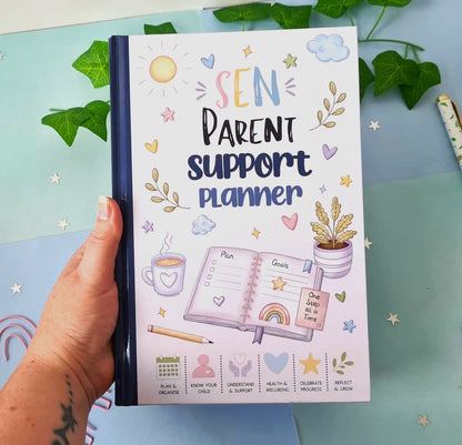 A hand holds a pastel-colored 'SEN Parent Support Planner' notebook. The cover features cute illustrations of a sun, clouds, stars, a coffee cup, an open notebook with a plan page, a small potted plant, and a rainbow, along with small icons at the bottom.